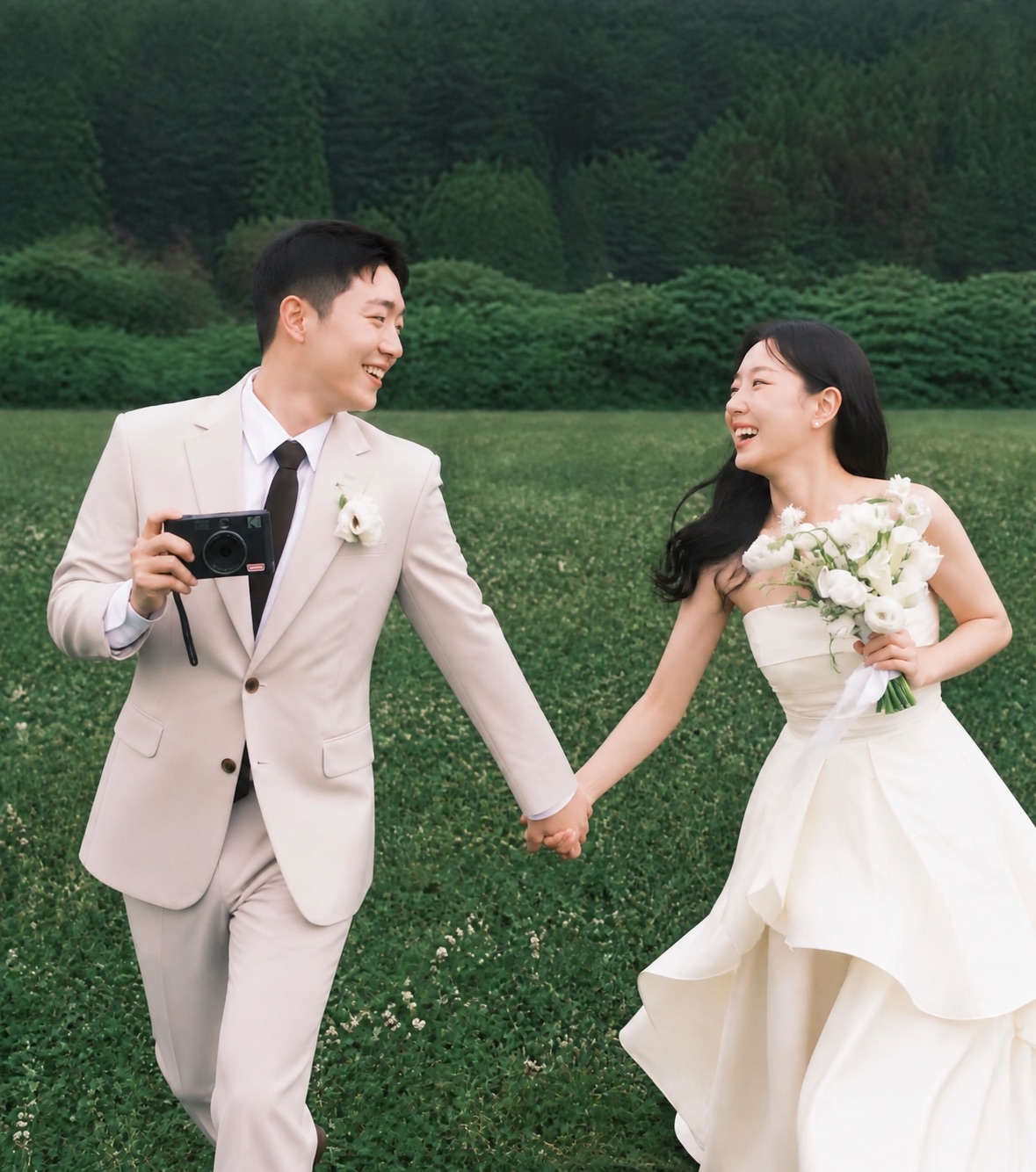 들판에서 카메라를 든 신랑과 부케를 든 신부
